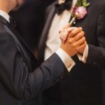 Two men dancing at a wedding reception in tuxedos.