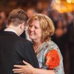 A woman is hugging her mother at a wedding reception.