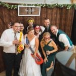 A group of people posing for a photo at a wedding reception in a photo booth.