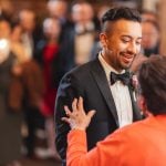 A man in a tuxedo is dancing with his mother at a wedding reception.