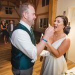 A couple feeding each other wedding cake at their reception.