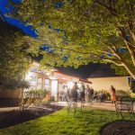 A group of people standing in a yard at night for a wedding.