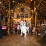 A bride and groom share their first dance at their wedding reception in a barn.