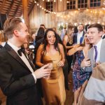 A group of people dancing at a wedding reception in a barn.