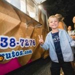 A young boy standing in front of an ice cream truck at a wedding reception.