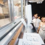 A bride and groom enjoying their wedding reception in front of a food truck.