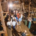 A group of people dancing at a wedding reception in a barn.