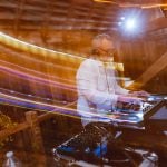 A man is playing a DJ in a wedding reception barn.