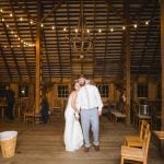 A bride and groom celebrating their wedding in a barn adorned with string lights during the reception.