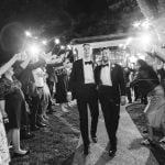 A black and white photo of a couple walking down the aisle during their wedding reception.