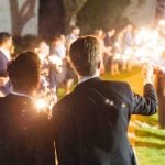 A group of men holding sparklers at a wedding reception.