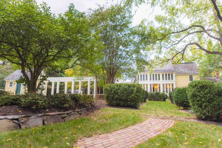 Pleasant Hill House, a yellow house with a brick walkway and trees, serves as an ideal wedding venue.