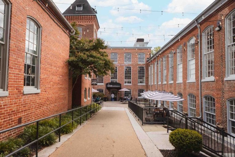 Savage Mill, a historic wedding venue, features an enchanting alleyway lined with charming brick buildings and crowned by a majestic clock tower.