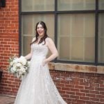 A wedding portrait of a bride smiling in front of Savage Mill.