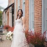 A bride has her portrait taken in front of the historic Savage Mill building.