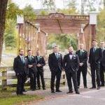 A group of groomsmen standing in front of a wedding venue.