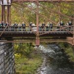 A wedding party posing for a portrait on a bridge at Savage Mill.