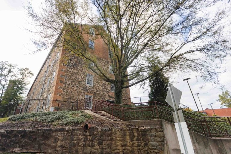 The picturesque Savage Mill, known for its architectural details, features a charming building with stairs that perfectly complement the lush tree in front of it.