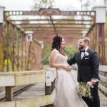 A wedding portrait of a bride and groom standing on a bridge at Savage Mill.