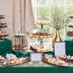 A table full of cupcakes and desserts on a green tablecloth at a wedding in Savage Mill.