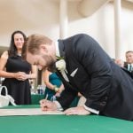 A man signing a wedding certificate in front of a group of people at Savage Mill.