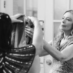 A candid woman getting her hair done in front of a mirror at Savage Mill for a wedding.