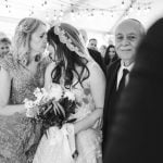 A bride kisses her father during a Savage Mill wedding ceremony.