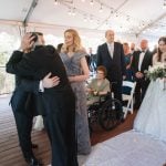 A man affectionately kisses his father during a wedding ceremony at Savage Mill.