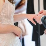 A wedding ceremony at Savage Mill, with the bride and groom exchanging their wedding rings.