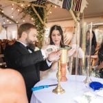 A wedding ceremony at Savage Mill, with the bride and groom lighting a candle in a tent.