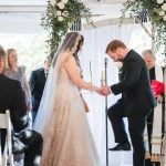 A bride and groom standing under a tent during a Savage Mill wedding ceremony.