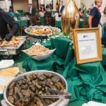 Guests at a wedding reception in Savage Mill gathered around a buffet table, enjoying the delicious spread and engaging in lively conversation.