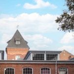 A brick building with a clock tower in the background at Savage Mill, providing a picturesque backdrop for wedding photos and capturing minute details.