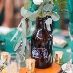 A wedding table setting at Savage Mill, featuring exquisite details. The green table is adorned with a glass jug and eucalyptus, creating a stunning centerpiece.