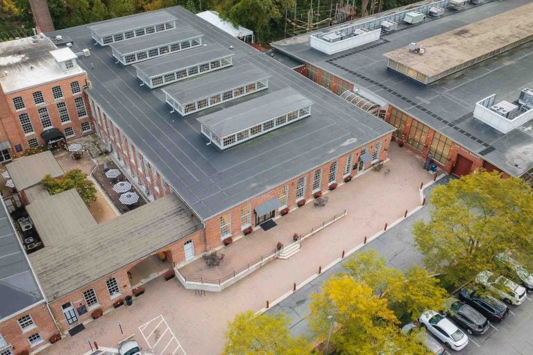 An aerial view of a brick building with parked cars at Savage Mill.