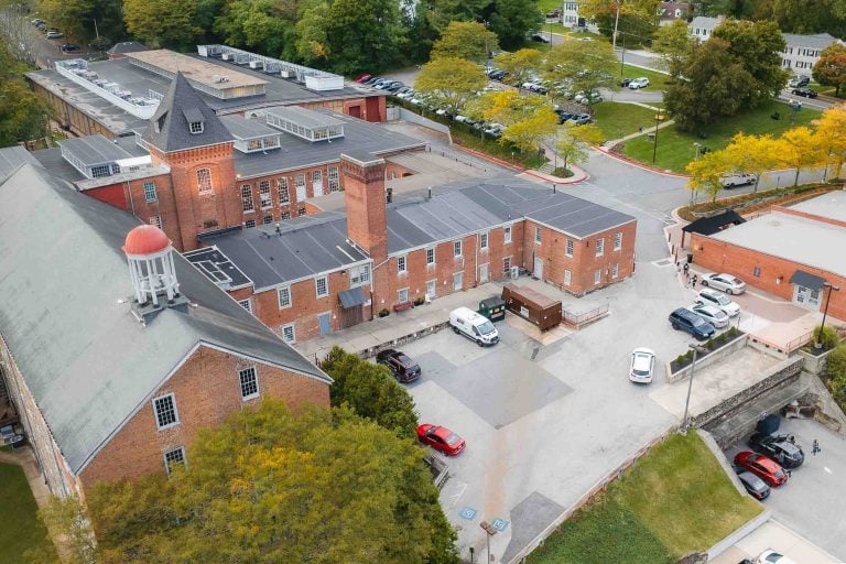 An aerial view of the Savage Mill, a brick building with cars parked in front of it.