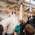 At the Savage Mill wedding reception, a man elegantly carries a bride in her stunning wedding dress.