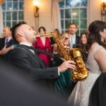 A couple performing a lively saxophone duet at their Savage Mill wedding reception.