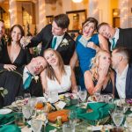 A group of people posing for a photo at a wedding reception in the Great Room at Savage Mill.