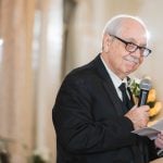 An older man giving a speech at a wedding reception.