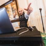 A wedding DJ with a laptop in front of him at Savage Mill.