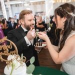 A bride and groom sharing a sweet moment while feeding each other cake at their wedding reception at Savage Mill.