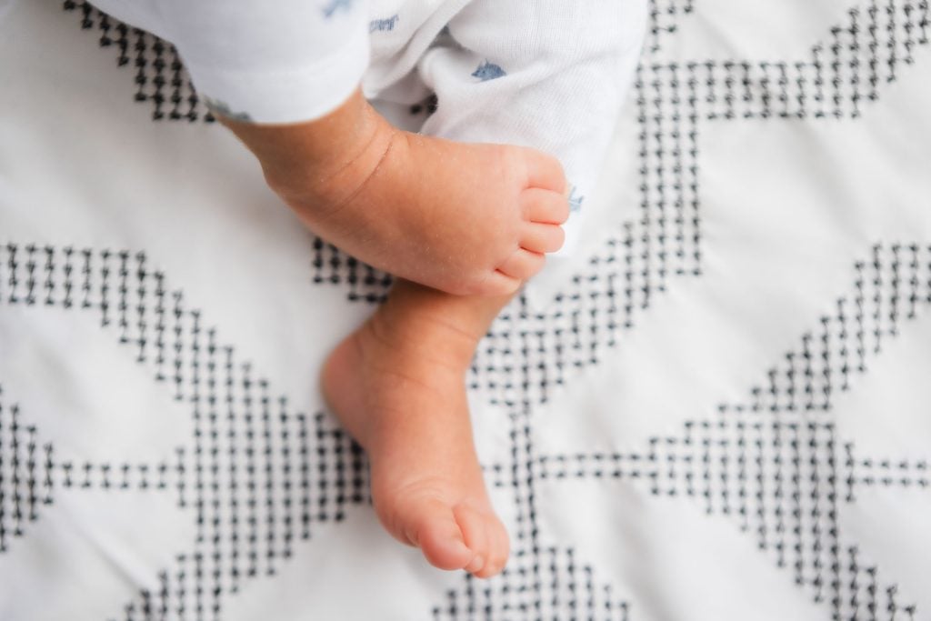 A newborn's feet resting on a white and black blanket.