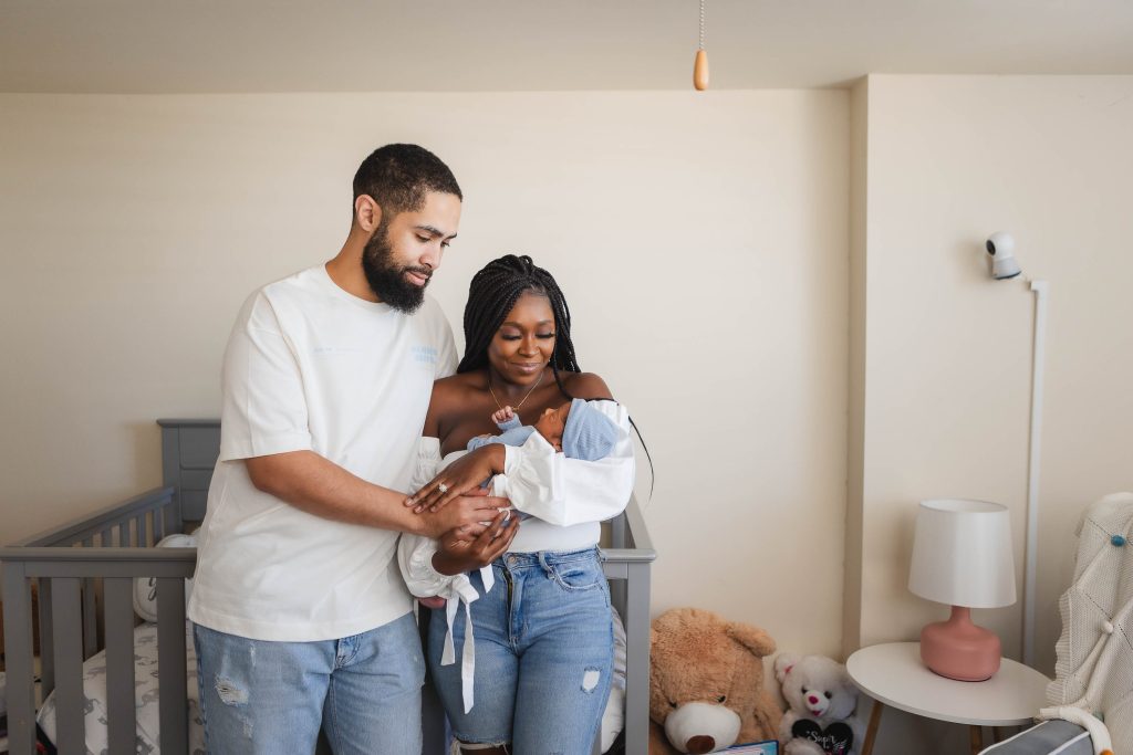 A family holding a newborn baby in a nursery while capturing heartwarming portraits.