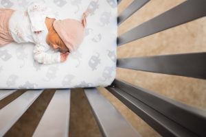 A newborn sleeping peacefully in a crib in the family home.