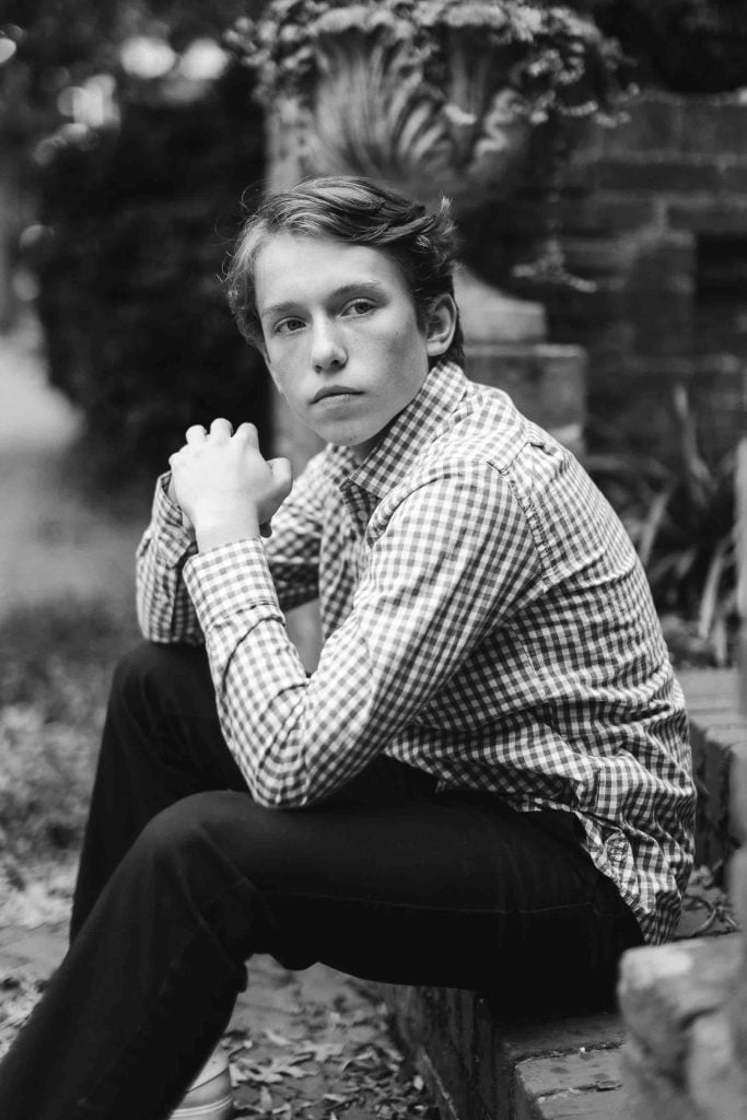 A black and white photo of a young man sitting on steps in Downtown Annapolis.