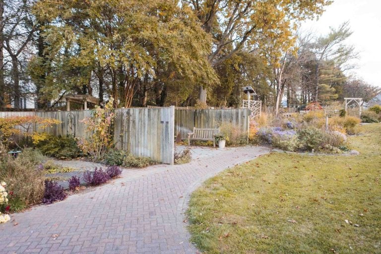 A brick walkway in Green Spring Gardens leads to a wooden fence in Alexandria, Virginia.