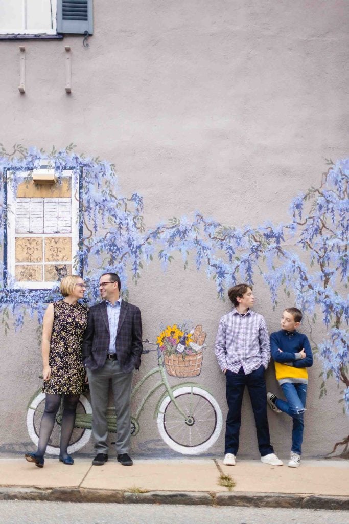 A family is posing in front of the famous Wisteria Mural on Fleet Street in Downtown Annapolis for their portraits.