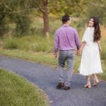 An engaged couple walking down a path in the beautiful Patuxent Research Refuge in Maryland, surrounded by the stunning sunset.