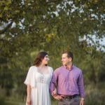 An engaged couple standing next to each other in a park at sunset, capturing beautiful engagement photos in Maryland.